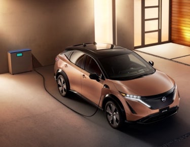 Nissan ARIYA plugged-in and charging outside a home | Hubler Nissan in Indianapolis IN